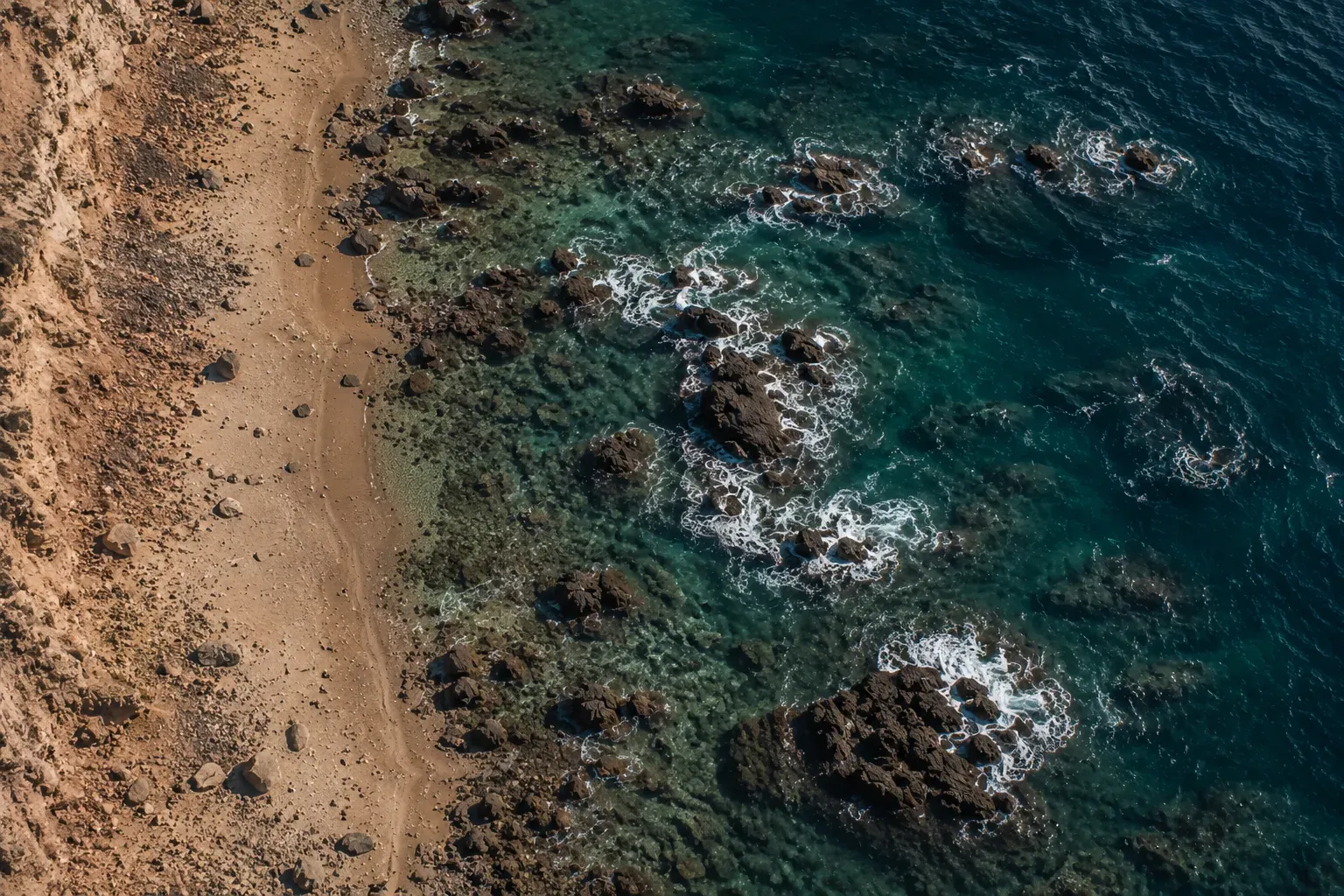 Vista aérea de la costa a pleno día, agua turquesa sobre roca